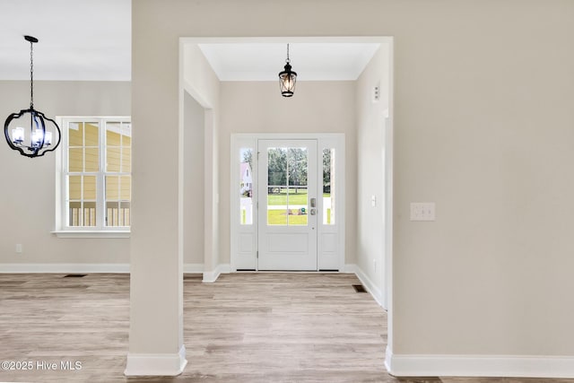 foyer with baseboards, wood finished floors, a chandelier, and ornamental molding