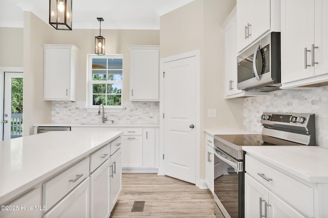 kitchen featuring sink, stainless steel appliances, backsplash, decorative light fixtures, and white cabinets