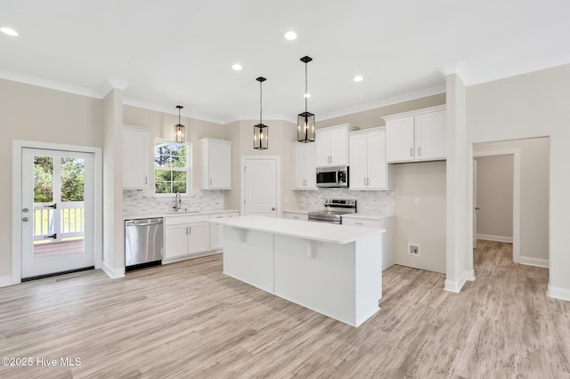 kitchen featuring a center island, a sink, white cabinetry, light countertops, and appliances with stainless steel finishes