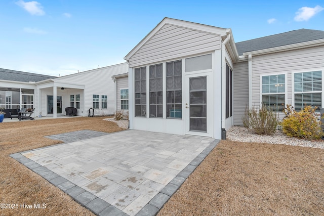 rear view of house featuring a lawn, a sunroom, and a patio