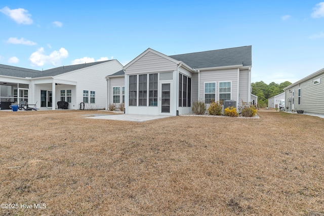 back of property with a yard, a patio area, and a sunroom