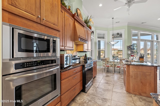 kitchen with a center island, decorative light fixtures, stainless steel appliances, ornamental molding, and dark stone countertops