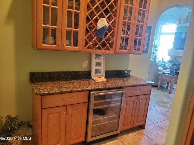 kitchen featuring beverage cooler, light tile patterned floors, and dark stone counters