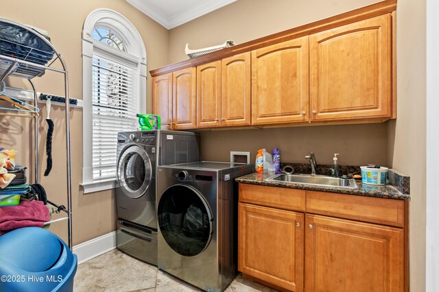 clothes washing area featuring cabinets, a healthy amount of sunlight, ornamental molding, sink, and washing machine and clothes dryer