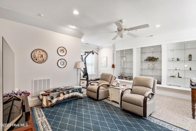 carpeted living room featuring ceiling fan and ornamental molding