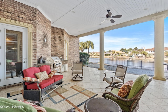 view of patio featuring ceiling fan, a water view, exterior kitchen, and grilling area