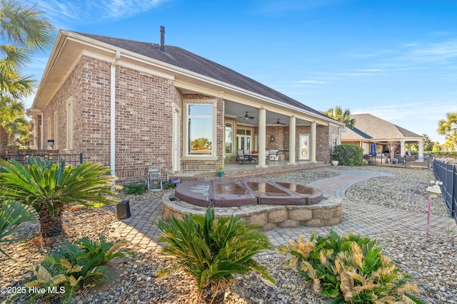 back of property with a patio area, ceiling fan, and an outdoor hot tub