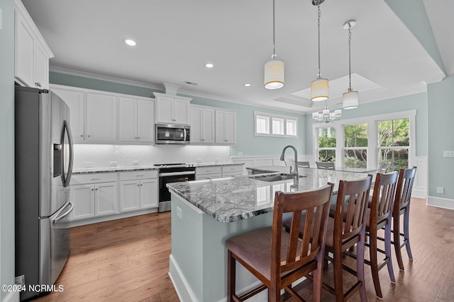 kitchen with a center island with sink, sink, white cabinetry, and stainless steel appliances