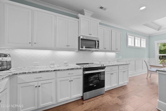 kitchen featuring light stone counters, appliances with stainless steel finishes, light wood-type flooring, white cabinets, and ornamental molding