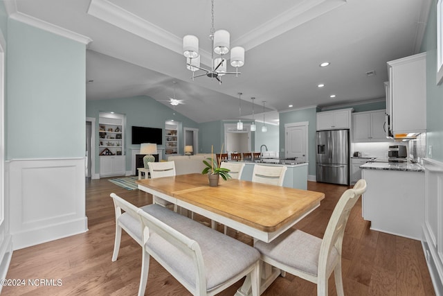 dining room featuring built in shelves, sink, dark wood-type flooring, crown molding, and ceiling fan with notable chandelier