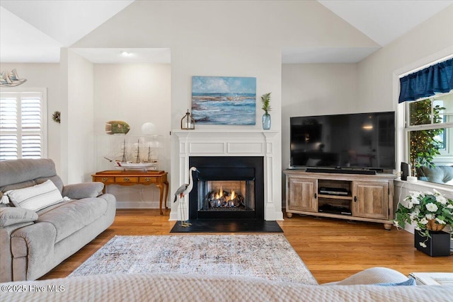 living room with vaulted ceiling, light hardwood / wood-style floors, and plenty of natural light