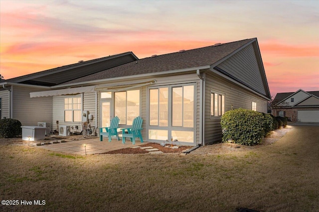 back house at dusk with a patio area and a yard