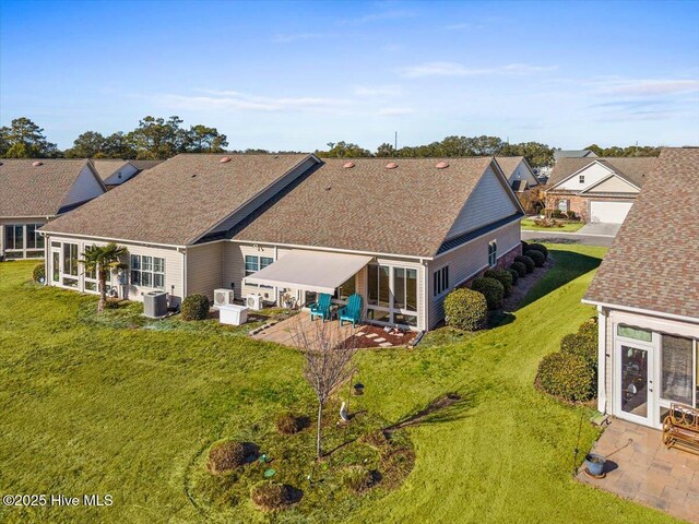 rear view of property featuring a patio, a shingled roof, a lawn, and central air condition unit