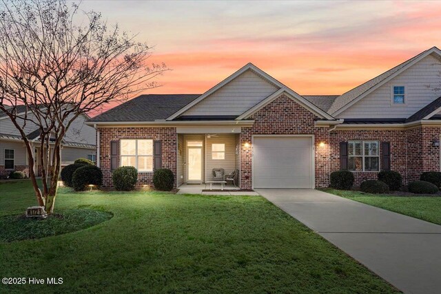 view of front facade with a lawn, brick siding, a shingled roof, concrete driveway, and an attached garage