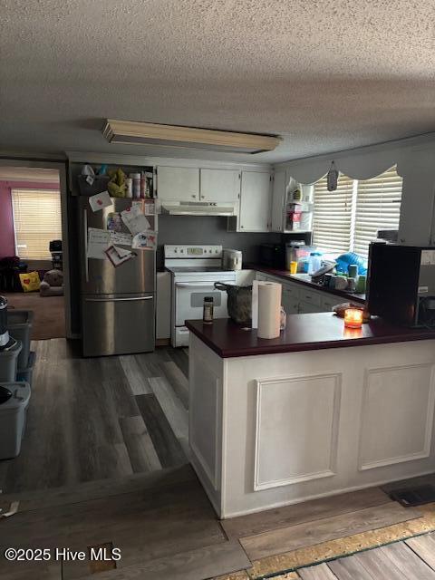 kitchen featuring white cabinets, a textured ceiling, stainless steel refrigerator, and electric stove