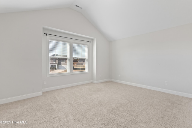 empty room with light colored carpet and vaulted ceiling