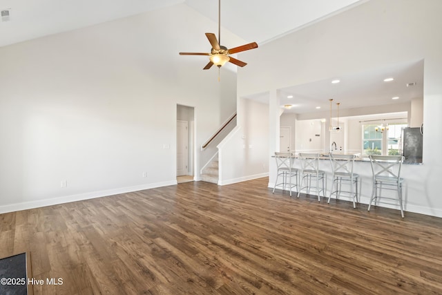 unfurnished living room featuring ceiling fan, dark hardwood / wood-style flooring, sink, and high vaulted ceiling