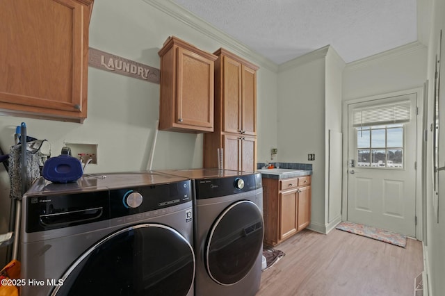 laundry area with cabinets, washing machine and clothes dryer, light hardwood / wood-style floors, crown molding, and a textured ceiling