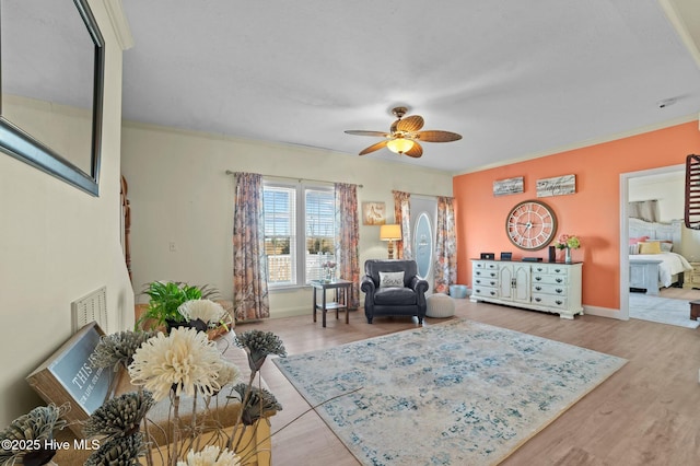 living room featuring ceiling fan, crown molding, and light hardwood / wood-style floors