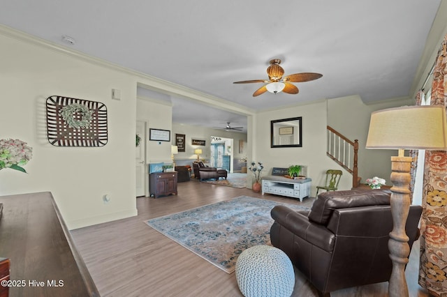 living room with crown molding, ceiling fan, and light wood-type flooring