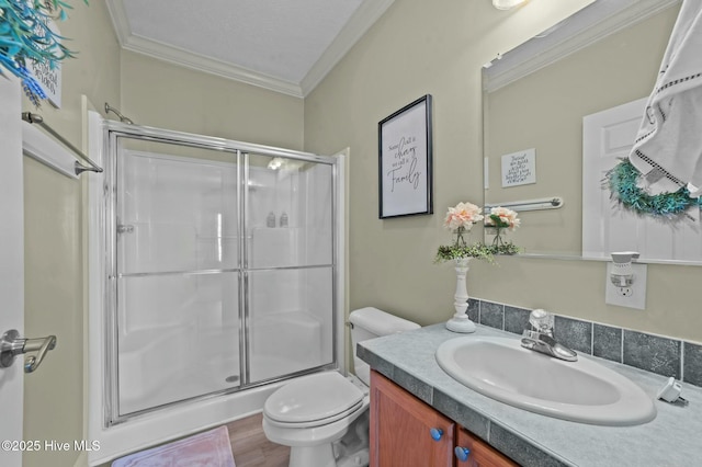 bathroom with a shower with door, vanity, wood-type flooring, ornamental molding, and toilet