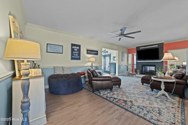 living room featuring crown molding, ceiling fan, a fireplace, and hardwood / wood-style floors