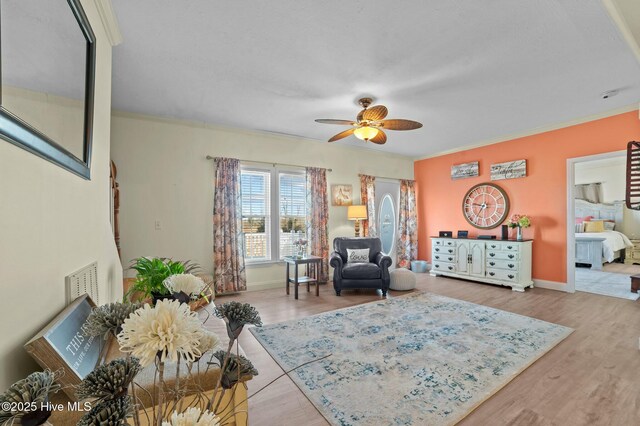 living room with wood-type flooring, ornamental molding, and ceiling fan