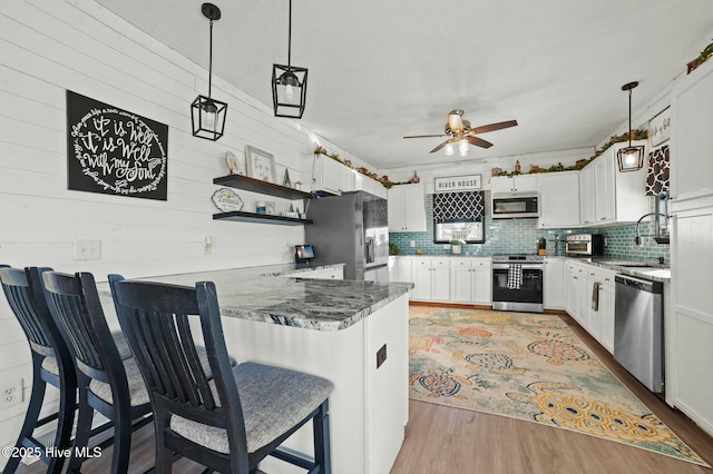 kitchen with hanging light fixtures, white cabinetry, appliances with stainless steel finishes, and a breakfast bar