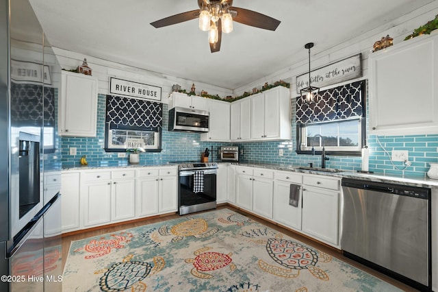 kitchen with white cabinetry, hanging light fixtures, stainless steel appliances, and sink