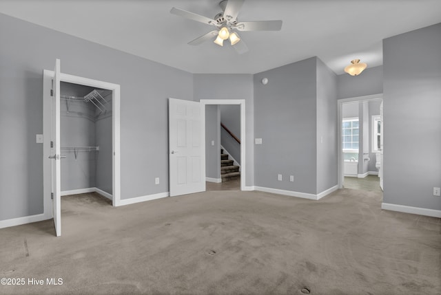 unfurnished bedroom featuring ceiling fan, light colored carpet, a walk in closet, and connected bathroom