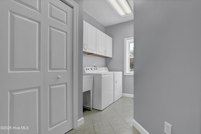 laundry area featuring washer and clothes dryer, light tile patterned floors, and cabinets