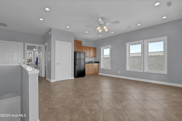 kitchen featuring ceiling fan, black fridge, light tile patterned floors, and plenty of natural light