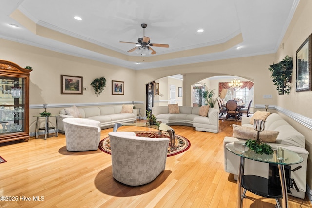 living room with light hardwood / wood-style flooring, a raised ceiling, and ornamental molding