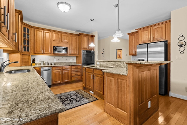 kitchen with pendant lighting, sink, light hardwood / wood-style flooring, appliances with stainless steel finishes, and a kitchen island