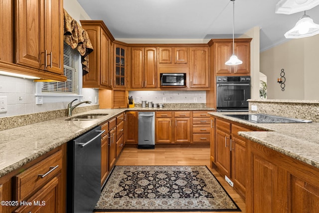 kitchen featuring sink, stainless steel appliances, light stone counters, light hardwood / wood-style flooring, and pendant lighting