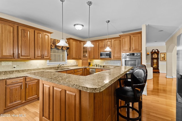 kitchen featuring a center island, light stone countertops, light wood-type flooring, decorative light fixtures, and stainless steel appliances