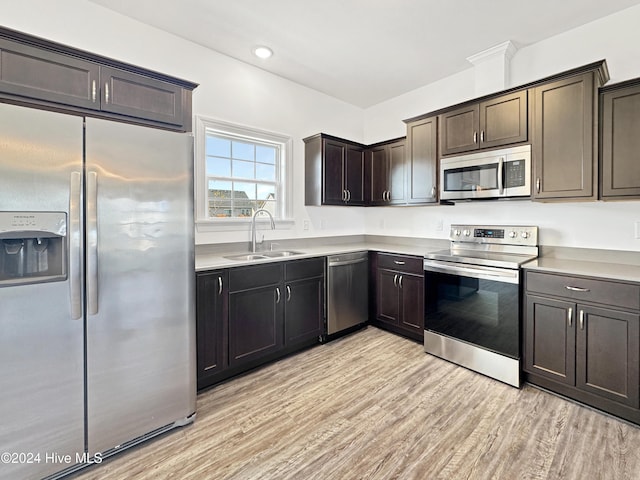 kitchen featuring appliances with stainless steel finishes, light wood-type flooring, dark brown cabinetry, and sink