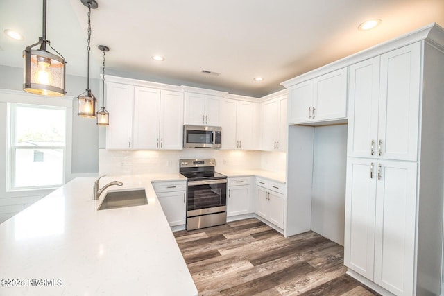 kitchen featuring hanging light fixtures, white cabinetry, sink, and appliances with stainless steel finishes