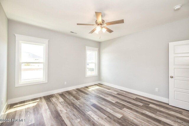 empty room featuring ceiling fan, plenty of natural light, and wood-type flooring