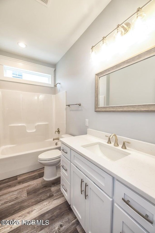 full bathroom with hardwood / wood-style floors, vanity, shower / bath combination, and toilet