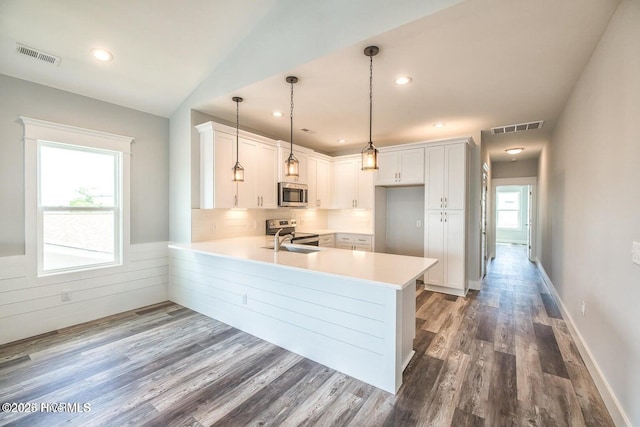 kitchen with a wealth of natural light, white cabinets, pendant lighting, and appliances with stainless steel finishes