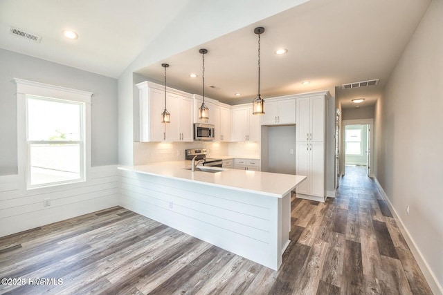 kitchen featuring white cabinets, pendant lighting, stainless steel appliances, and kitchen peninsula