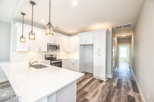 kitchen featuring kitchen peninsula, stainless steel appliances, sink, pendant lighting, and white cabinets