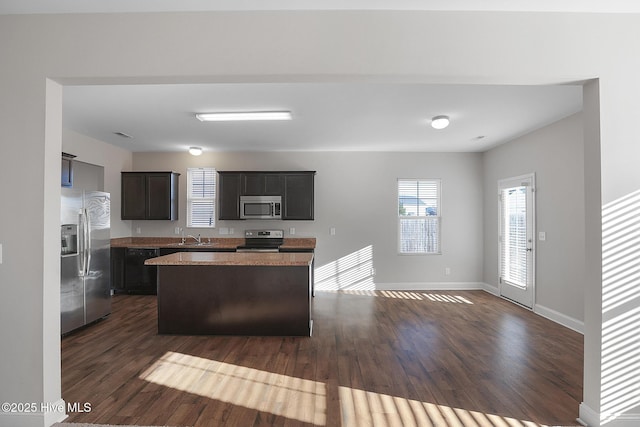 kitchen featuring appliances with stainless steel finishes, dark hardwood / wood-style floors, a kitchen island, and sink