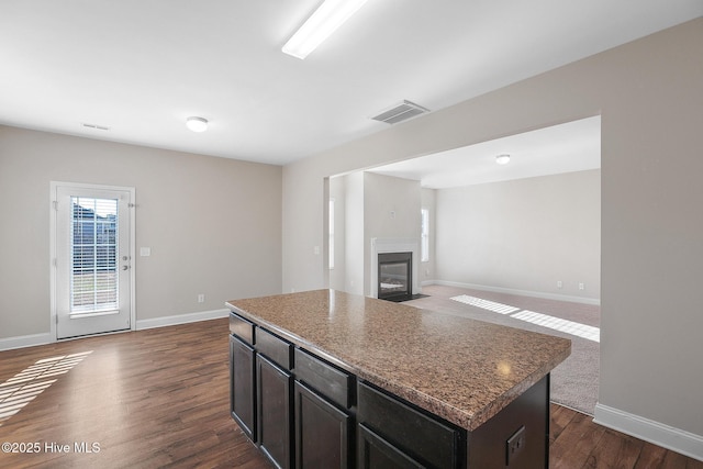 kitchen featuring a center island, dark wood-type flooring, and dark brown cabinets