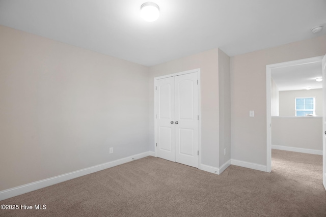 unfurnished bedroom featuring light colored carpet and a closet