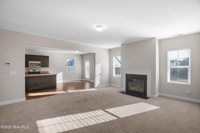 unfurnished living room featuring light carpet and plenty of natural light