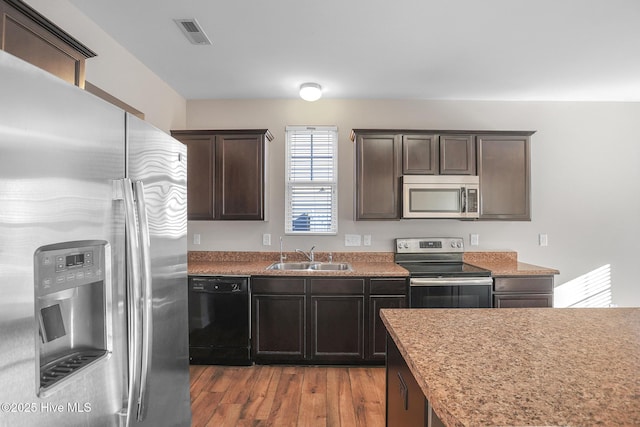 kitchen featuring light wood-type flooring, stainless steel appliances, dark brown cabinetry, and sink