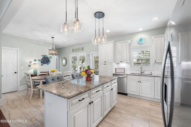 kitchen with white cabinets, hanging light fixtures, a kitchen island, and stainless steel appliances