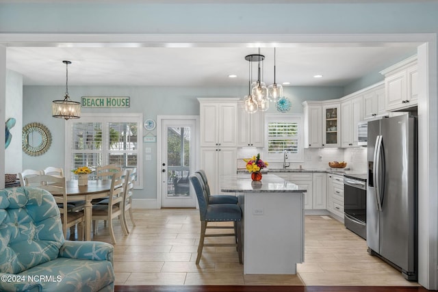 112 NE 28th St, Oak Island, NC 28465 - kitchen with stainless steel appliances, a chandelier, light stone countertops, a kitchen breakfast bar, and white cabinets